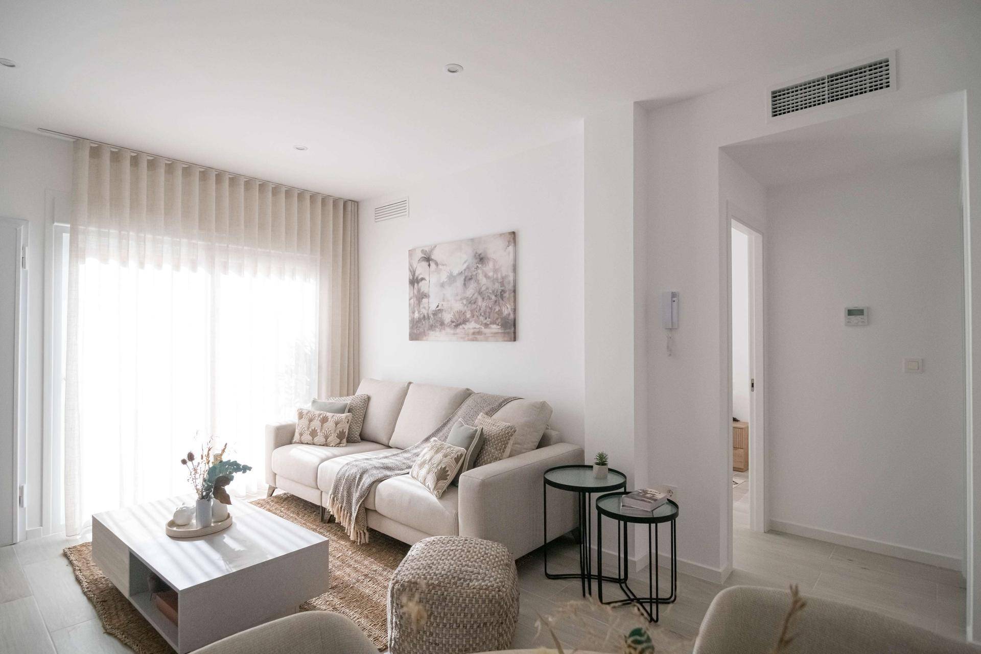Gemütliches Wohnzimmer mit hellem Sofa, modernen Möbeln und viel Tageslicht.