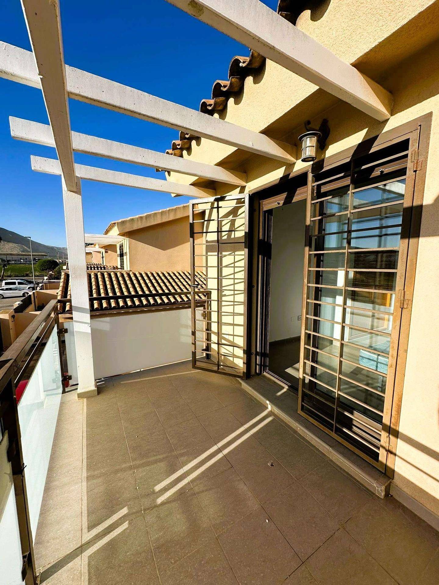 Geräumiger Balkon mit Fliesenboden, Pergola und Blick auf die Umgebung.
