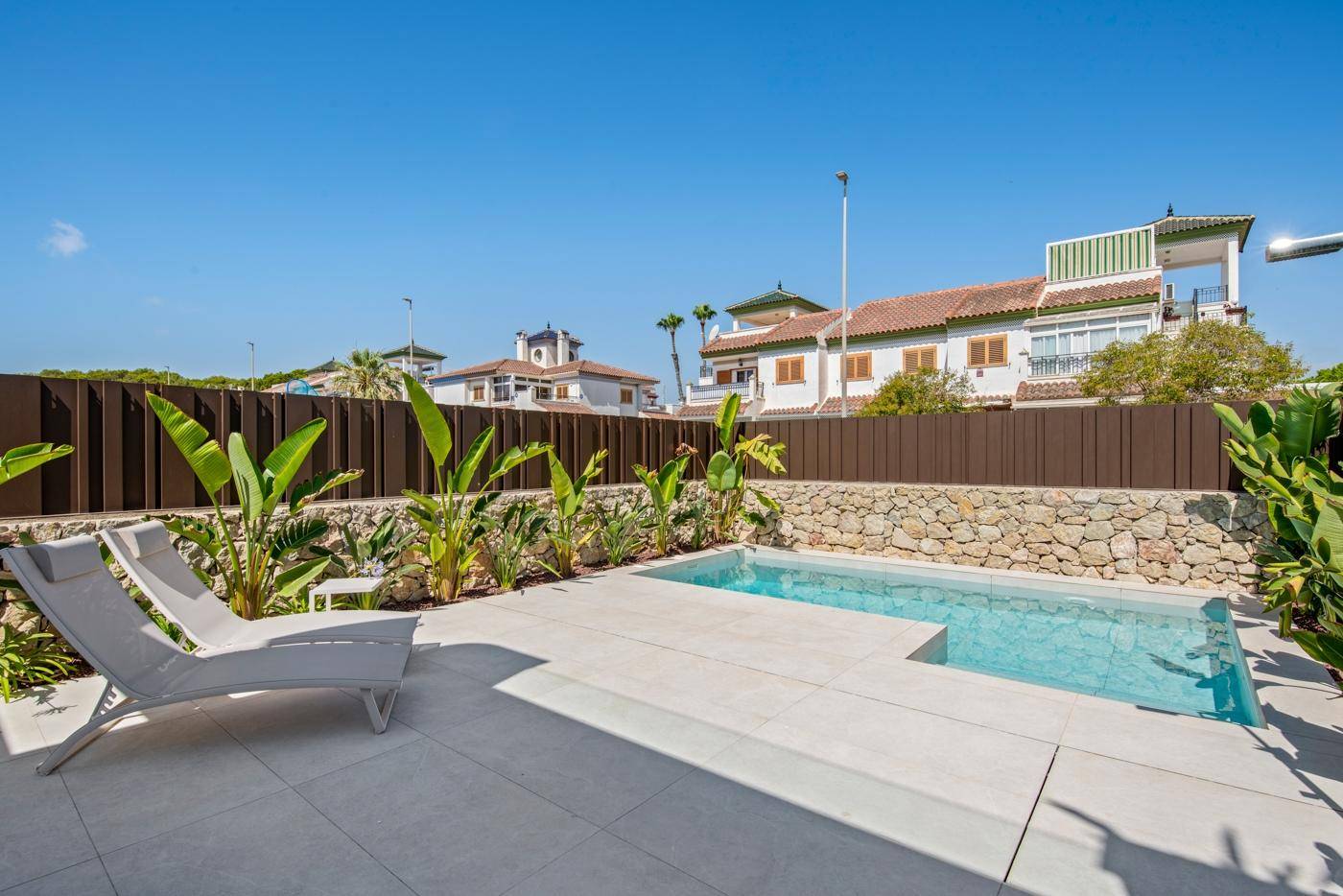 Geräumiger Poolbereich mit Liegestühlen und gefliester Terrasse, umgeben von mediterraner Bepflanzung.