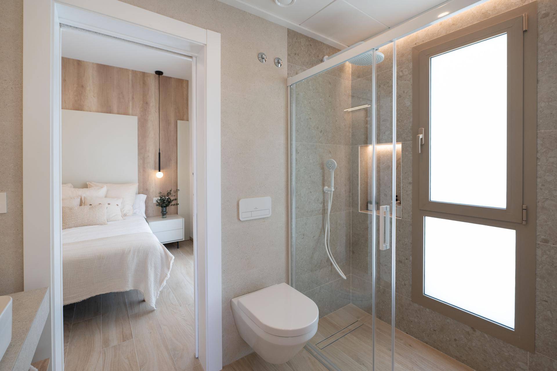 Modernes Badezimmer mit begehbarer Dusche, Wand-WC und Zugang zum Schlafzimmer.