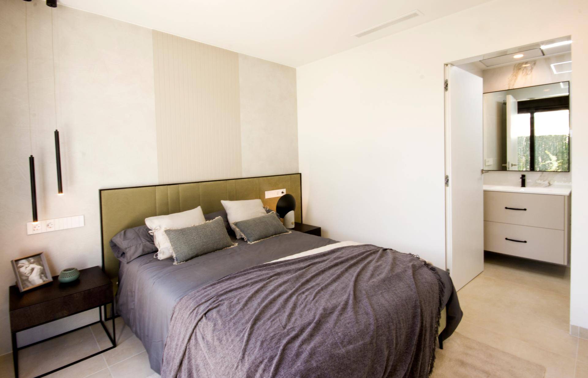Schlafzimmer mit direktem Zugang zu einem modernen Badezimmer mit Waschtisch.