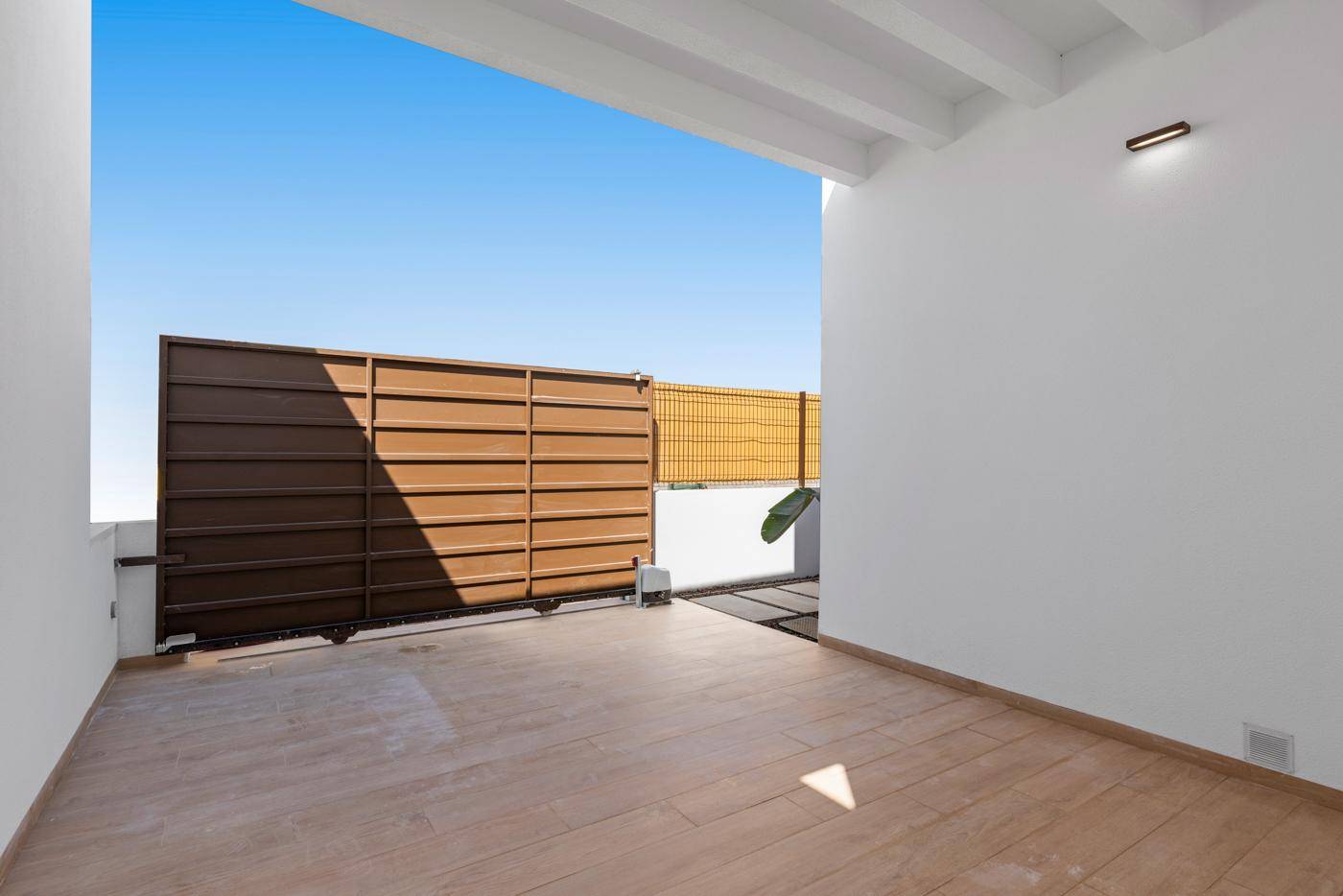 Überdachte Terrasse mit hellem Bodenbelag und Blick auf den privaten Außenbereich.