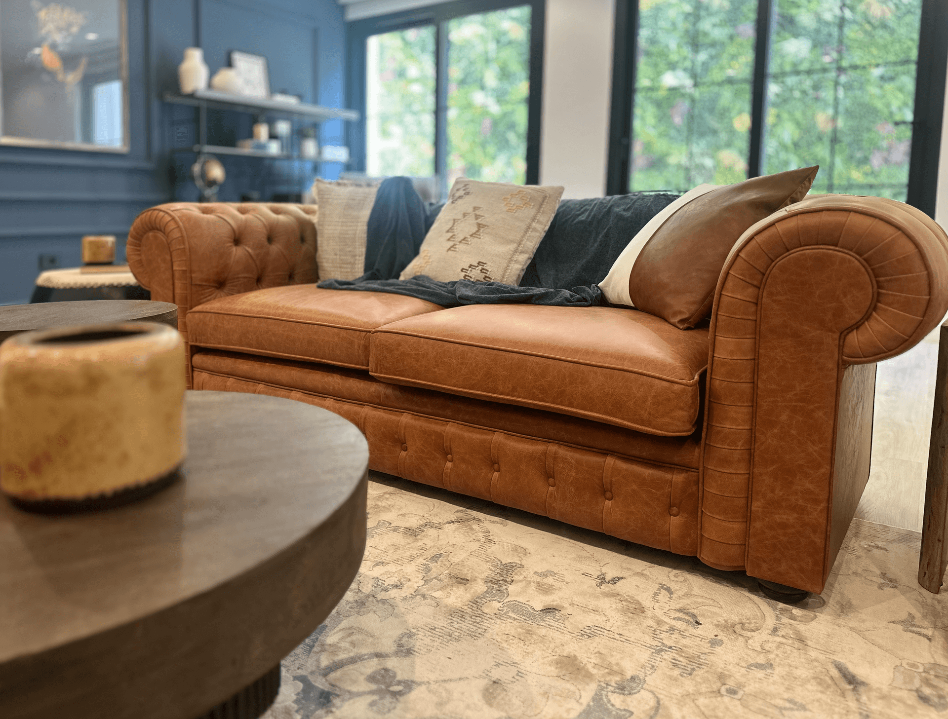 Klassisches Ledersofa in einem eleganten Wohnzimmer mit Teppich und großen Fenstern.