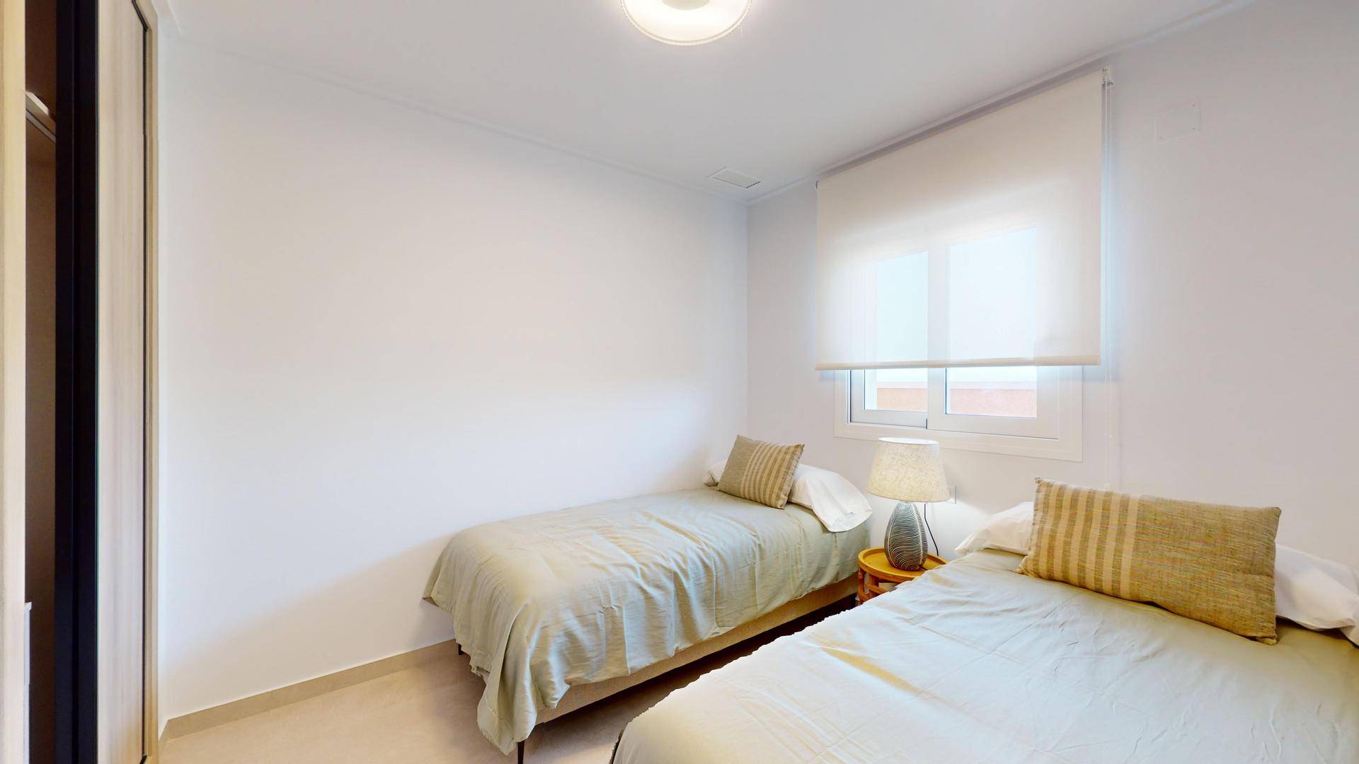 Helles Schlafzimmer mit zwei Einzelbetten und einem Fenster für natürliche Belichtung.