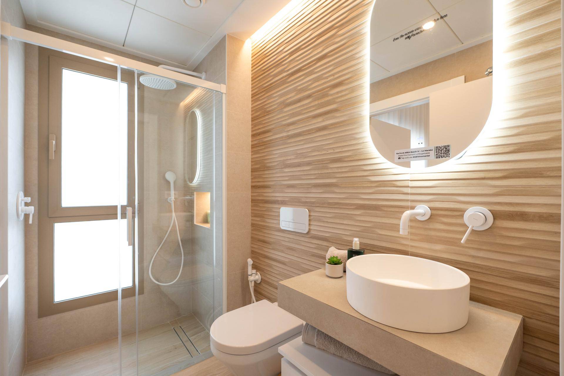 Modernes Badezimmer mit begehbarer Dusche, stilvollen Fliesen und beleuchtetem Spiegel.
