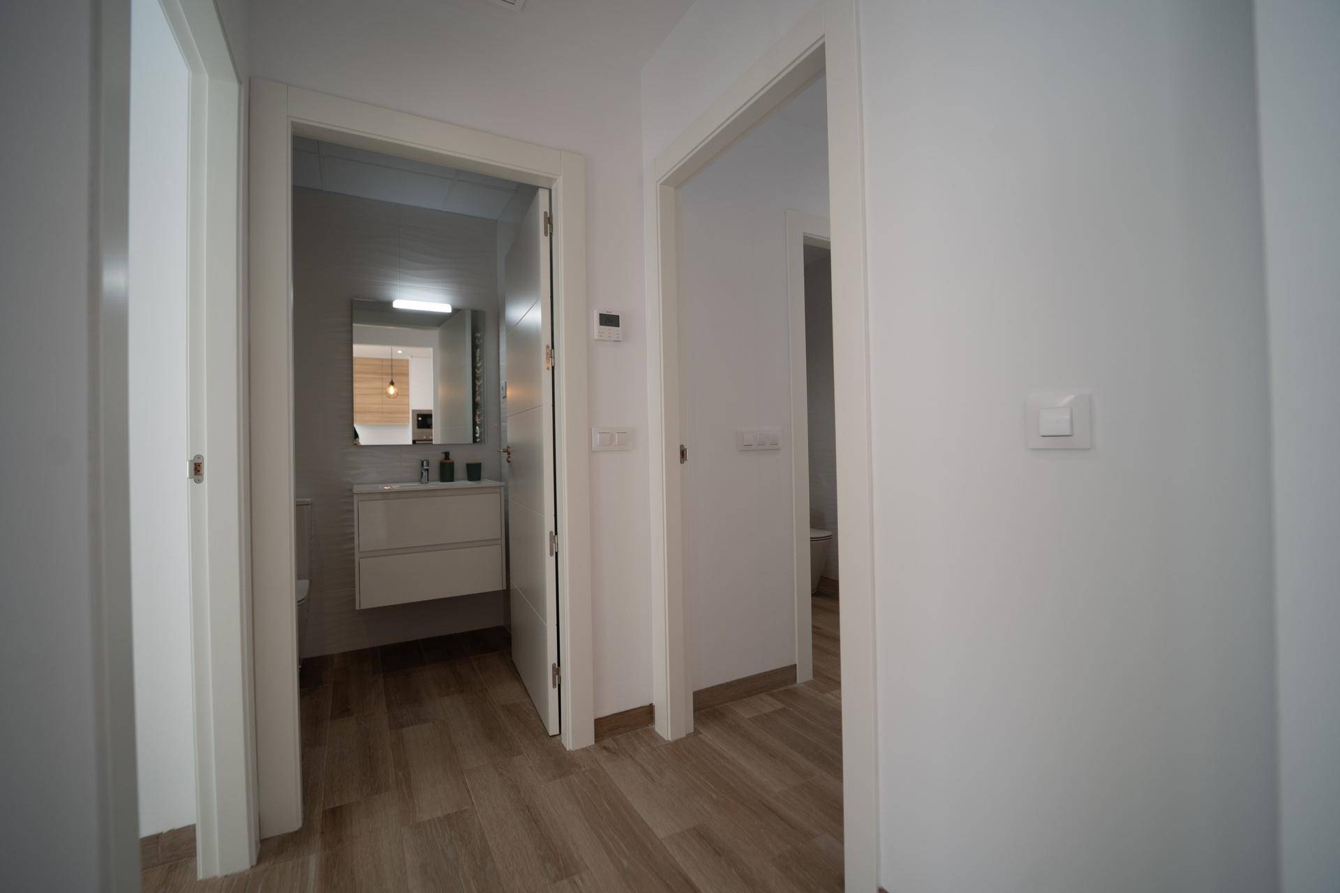 Heller Flur mit Laminatboden, der zu Badezimmer und weiteren Räumen führt.