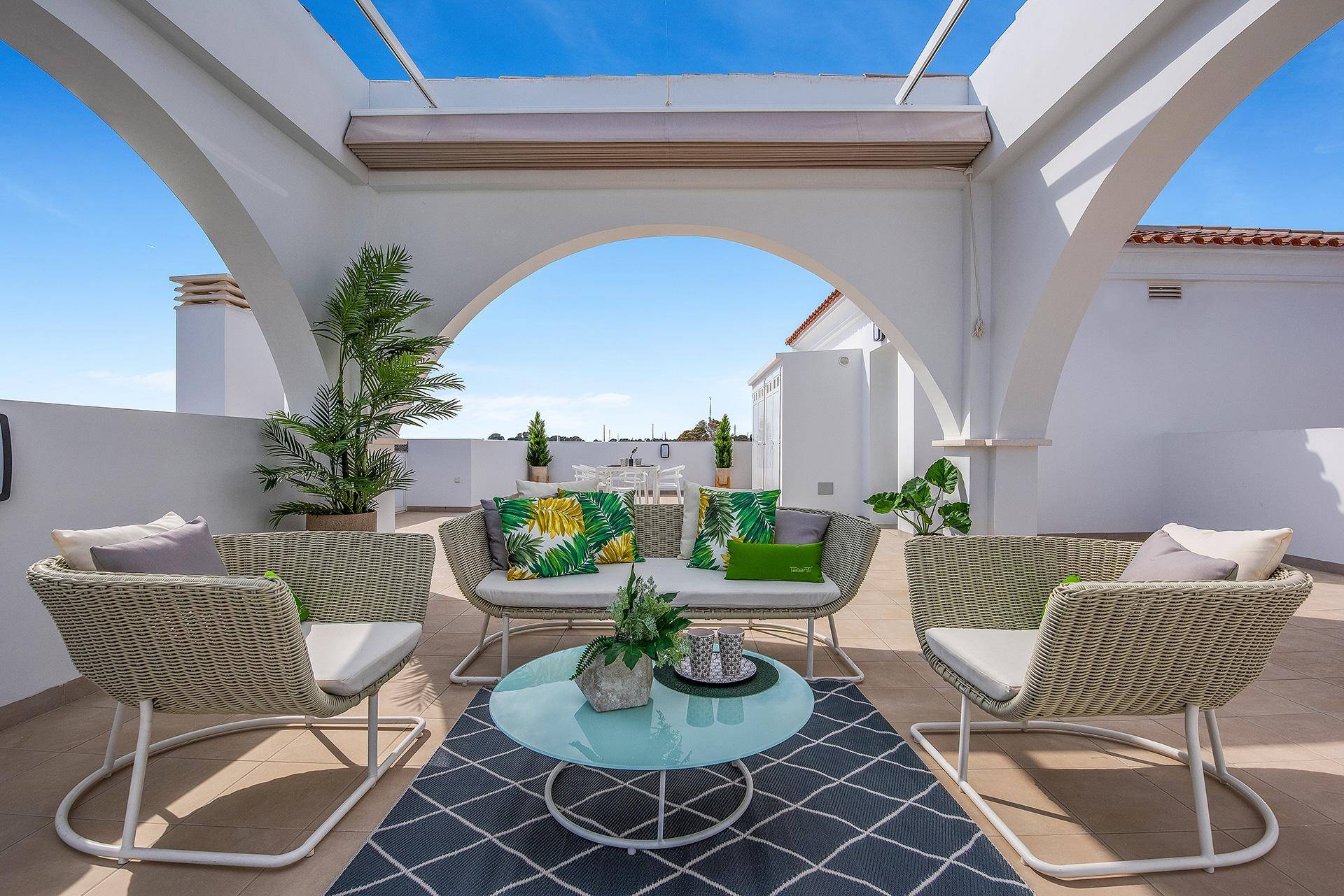 Überdachte Dachterrasse mit bequemen Loungemöbeln und weitem Blick unter einem blauen Himmel.