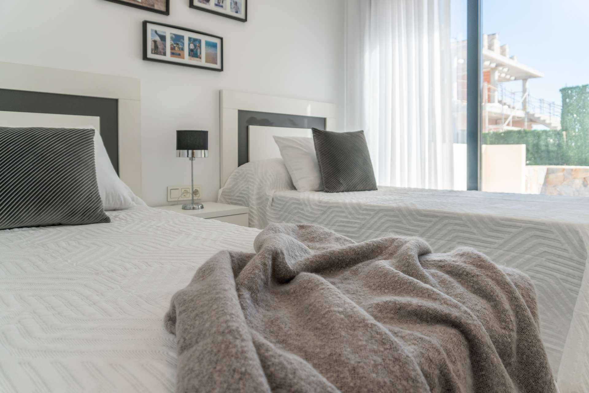 Helles Schlafzimmer mit zwei Einzelbetten, modernen Nachttischen und Fenster.