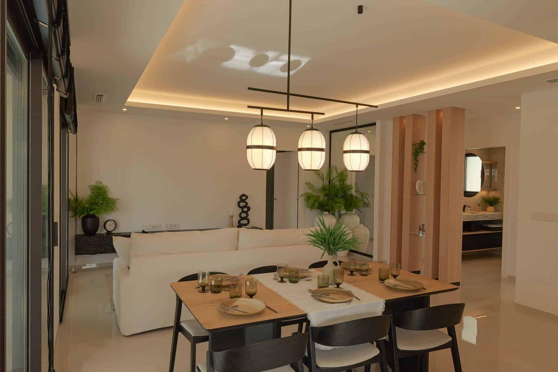 Heller Essbereich mit modernem Holztisch und Designerleuchten, offen zum Wohnzimmer.