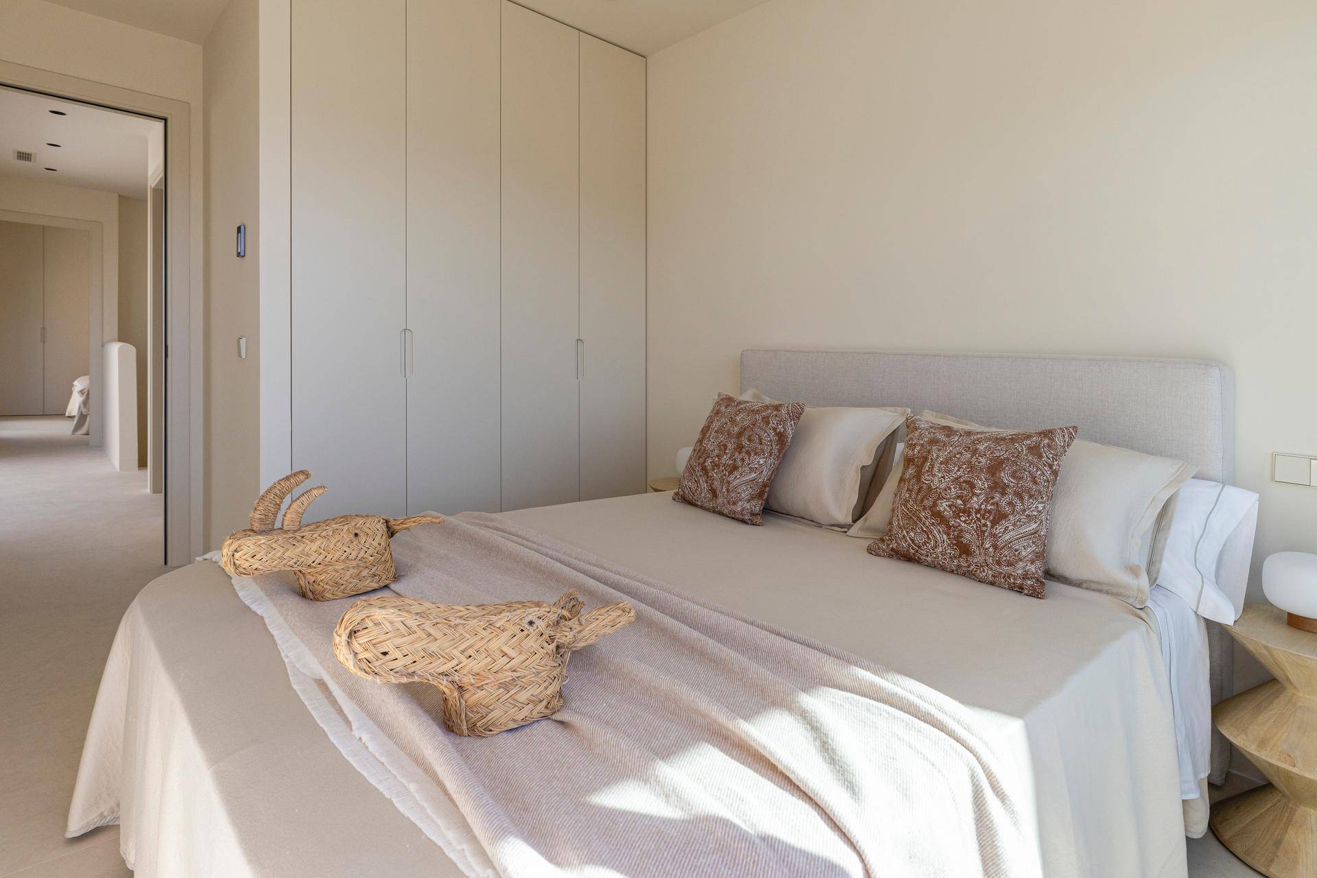 Helles Schlafzimmer mit Einbauschränken und Zugang zu einem Balkon.
