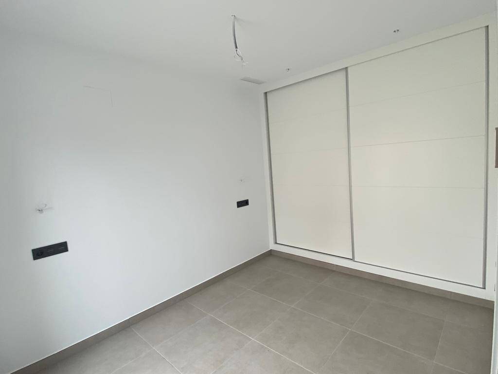 Helles Zimmer mit integriertem Einbauschrank und modernem Fliesenboden.