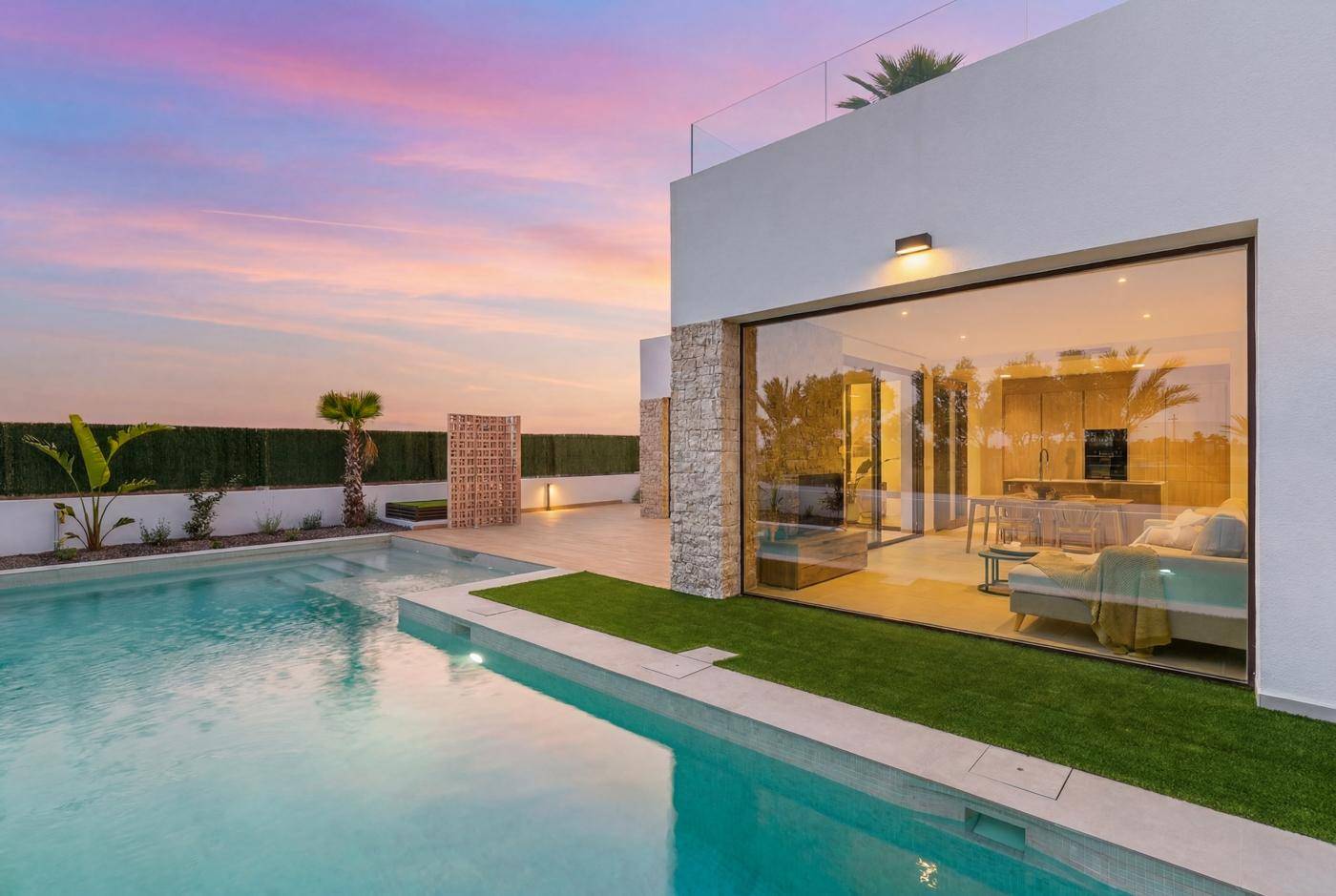 Außenansicht der modernen Villa mit großzügigem Pool und Blick auf die umliegende Landschaft bei Sonnenuntergang.