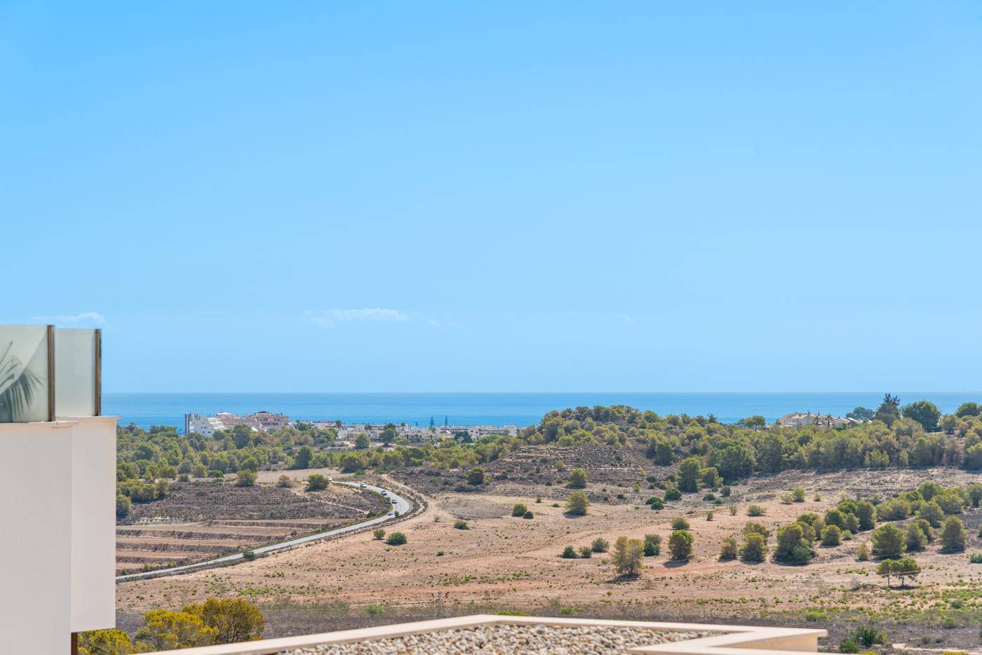 Panoramablick auf das weite Meer und die hügelige Landschaft unter klarem Himmel.