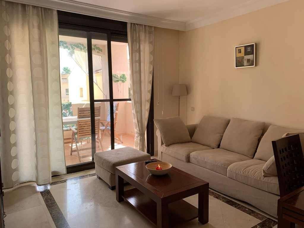 Helles Wohnzimmer mit beigem Sofa, Couchtisch und Zugang zu einem sonnigen Balkon.