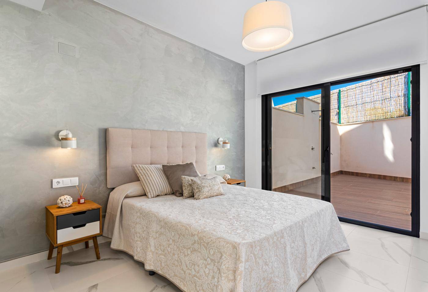 Helles Schlafzimmer mit Doppelbett, modernem Dekor und Zugang zur Terrasse.