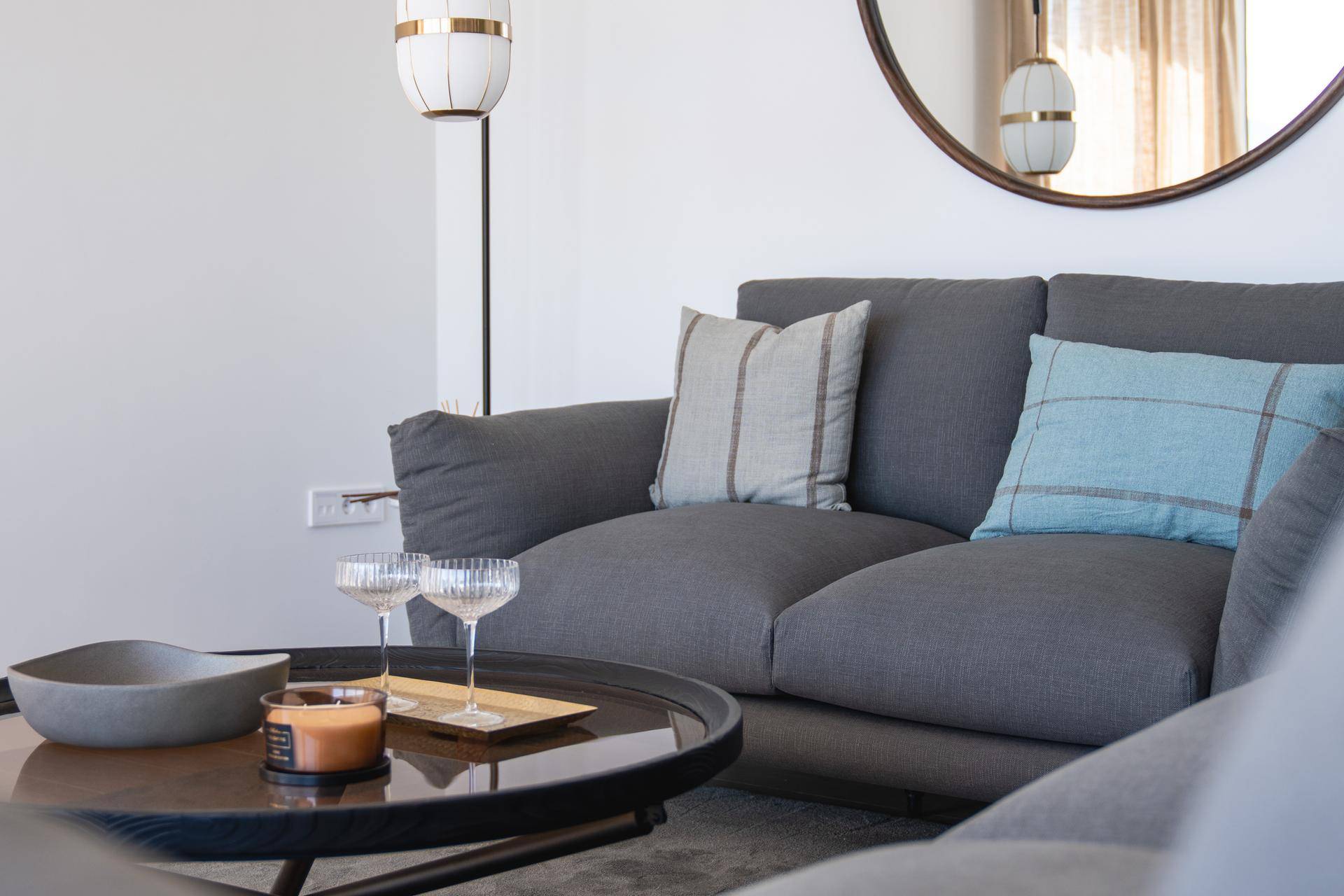 Gemütliche Sitzecke im Wohnzimmer mit grauem Sofa, Kissen und stilvoller Dekoration.