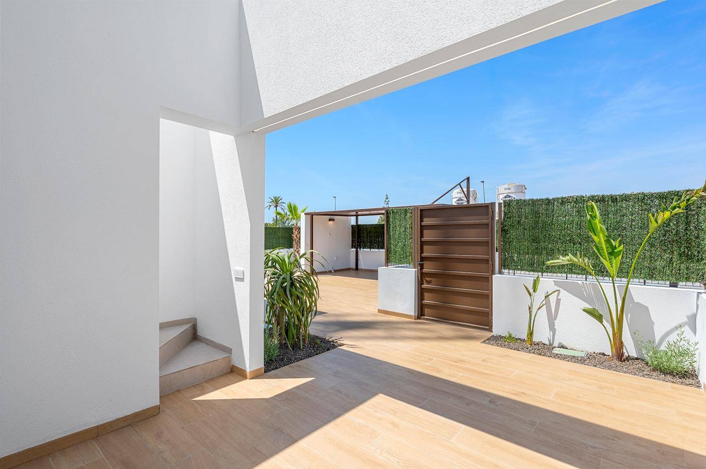 Offener Terrassenbereich mit Pflanzen und Blick auf den umzäunten Außenbereich.