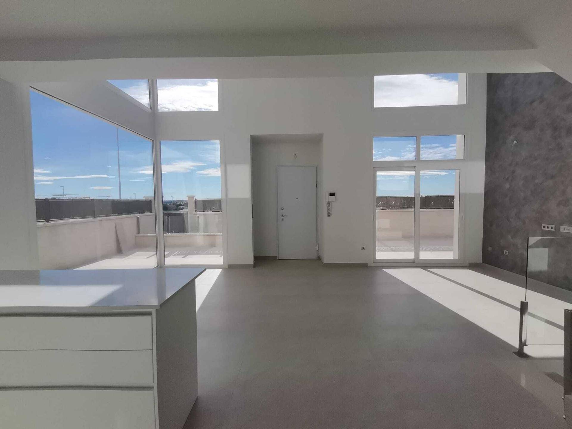 Geräumiger, heller Raum mit großen Fenstern und direktem Zugang zur Dachterrasse, ideal für Entspannung.