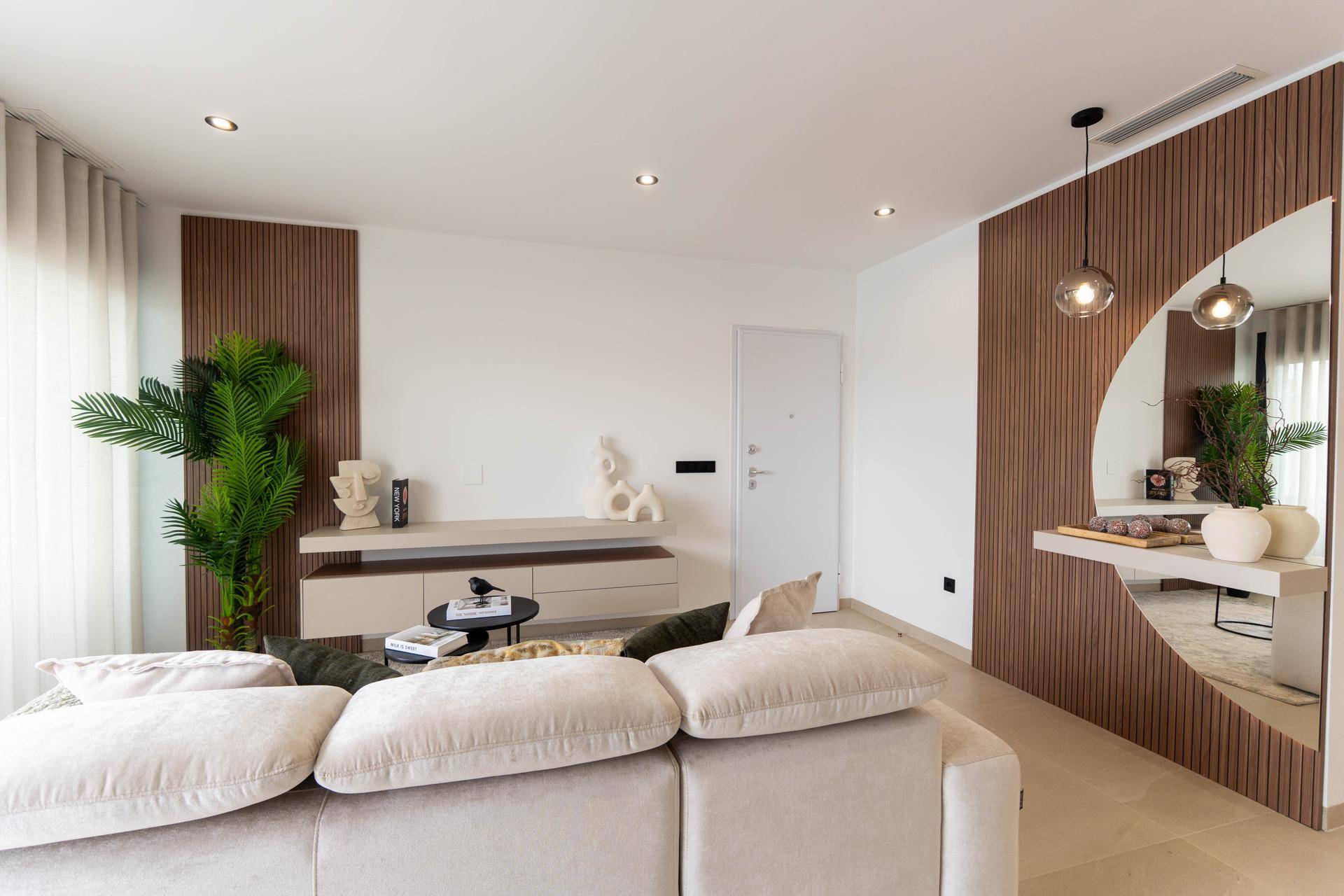 Heller Wohnbereich mit beigem Sofa, Holzwandverkleidung und dekorativen Elementen.