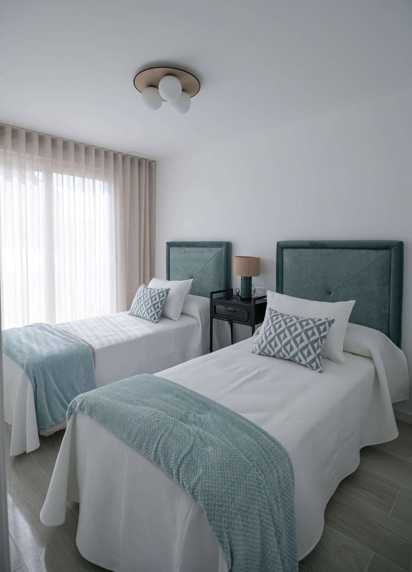 Helles Schlafzimmer mit zwei Einzelbetten, modernen Kopfteilen und viel Tageslicht.