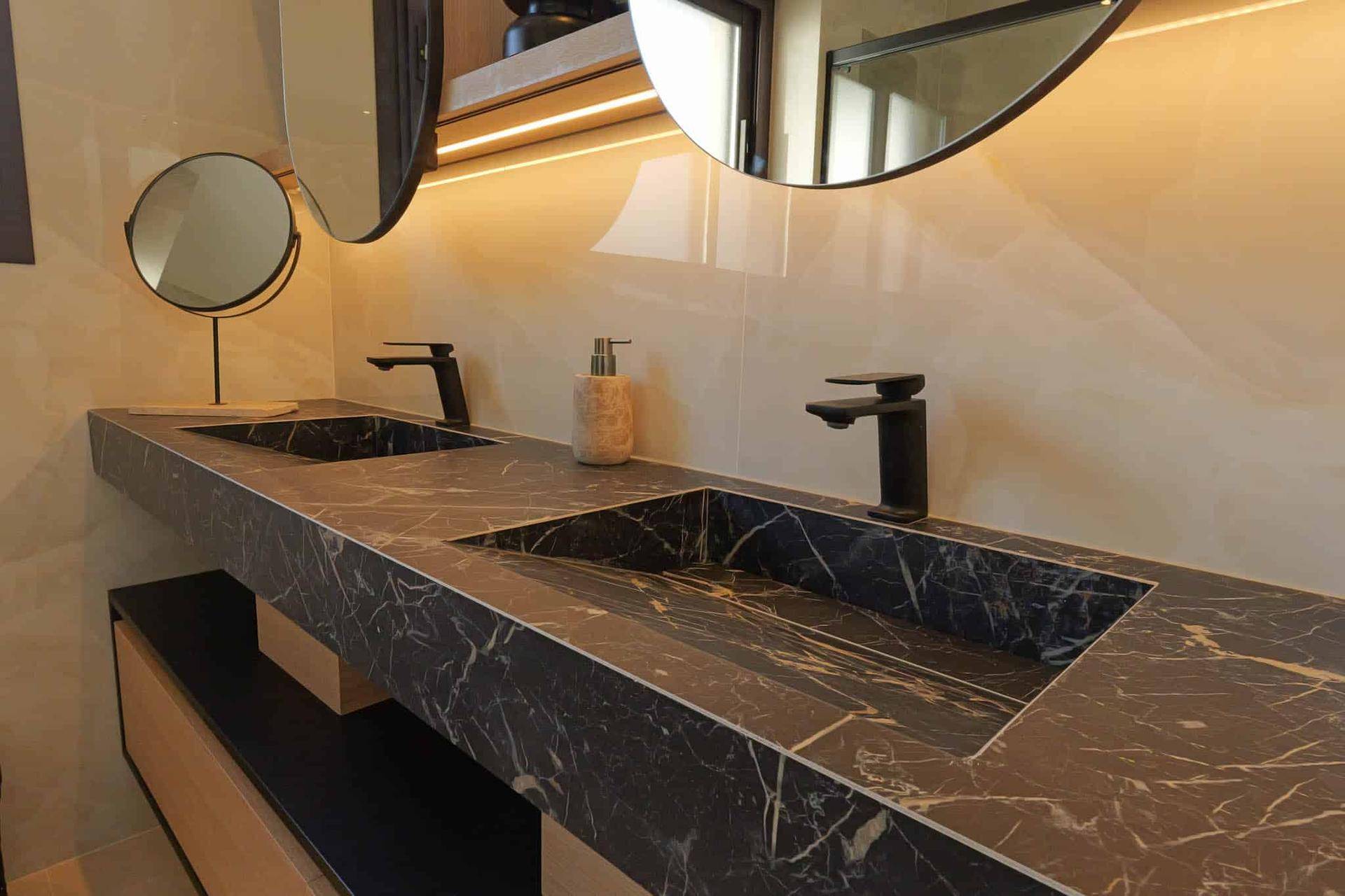 Luxuriöses Badezimmer mit Doppelwaschbecken aus schwarzem Marmor und modernen Armaturen.