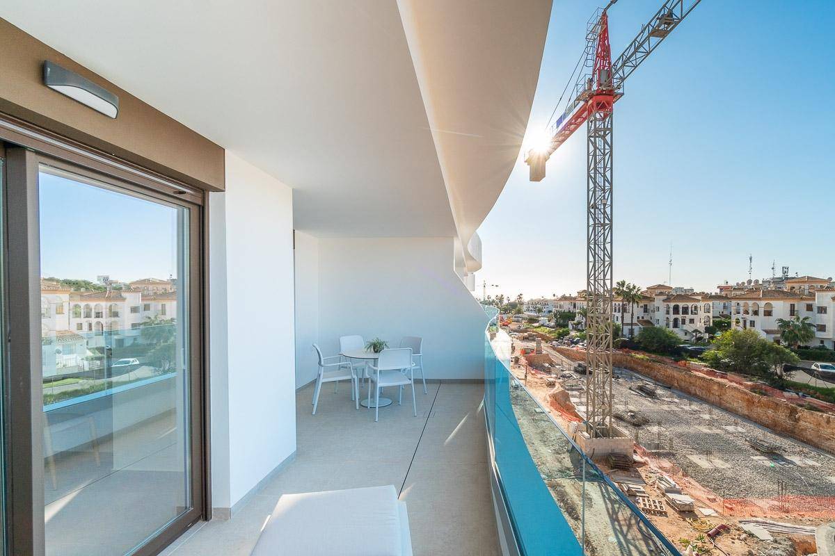 Sonniger Balkon mit Essbereich, Glasgeländer und weitem Blick über die umliegenden Gebäude.