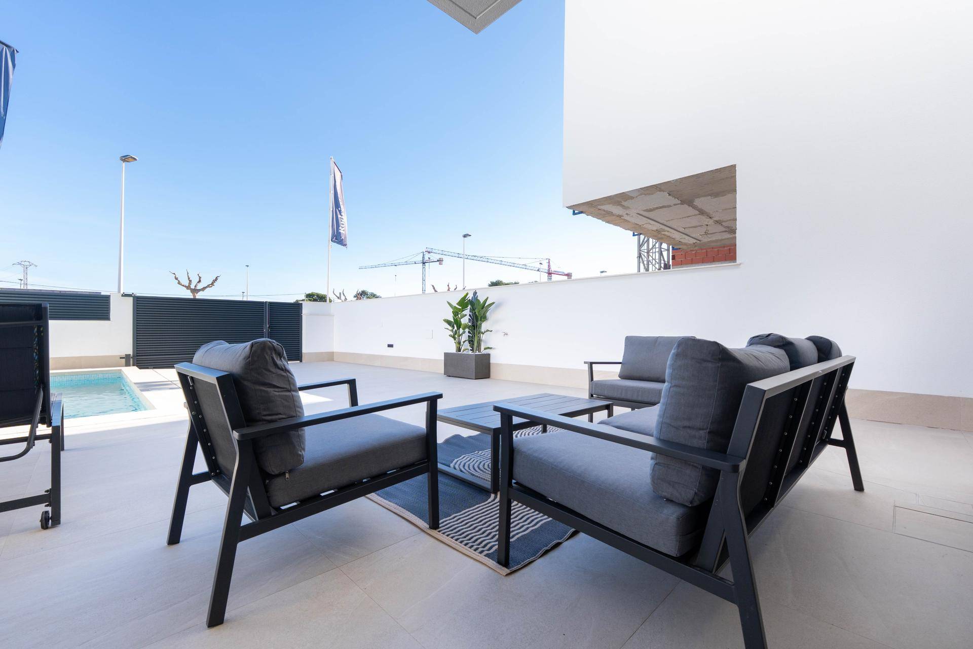 Moderne Sitzecke auf der Terrasse mit Blick auf den Pool und die Umgebung.
