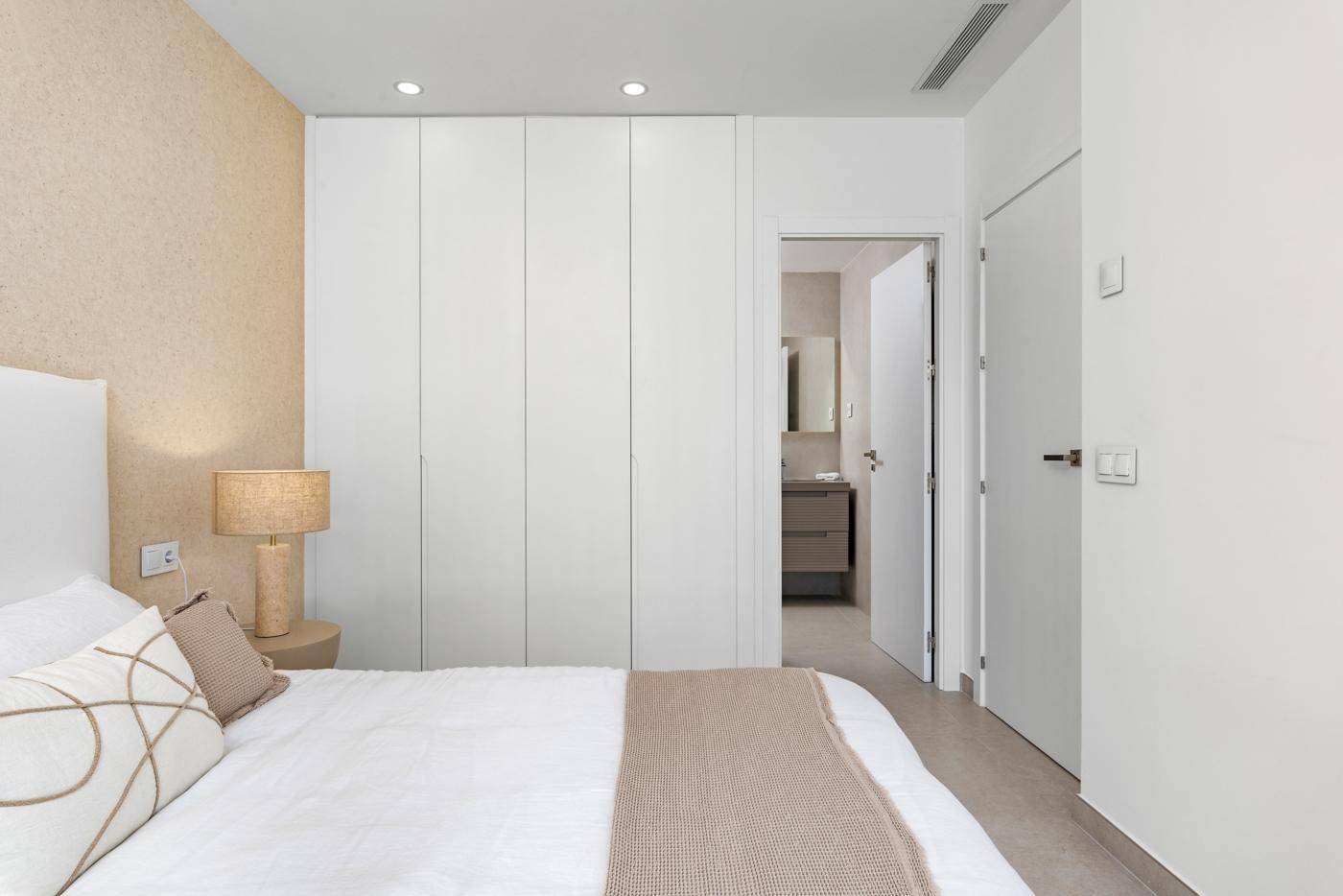 Modernes Schlafzimmer mit Einbauschränken und angrenzendem Badezimmerzugang.