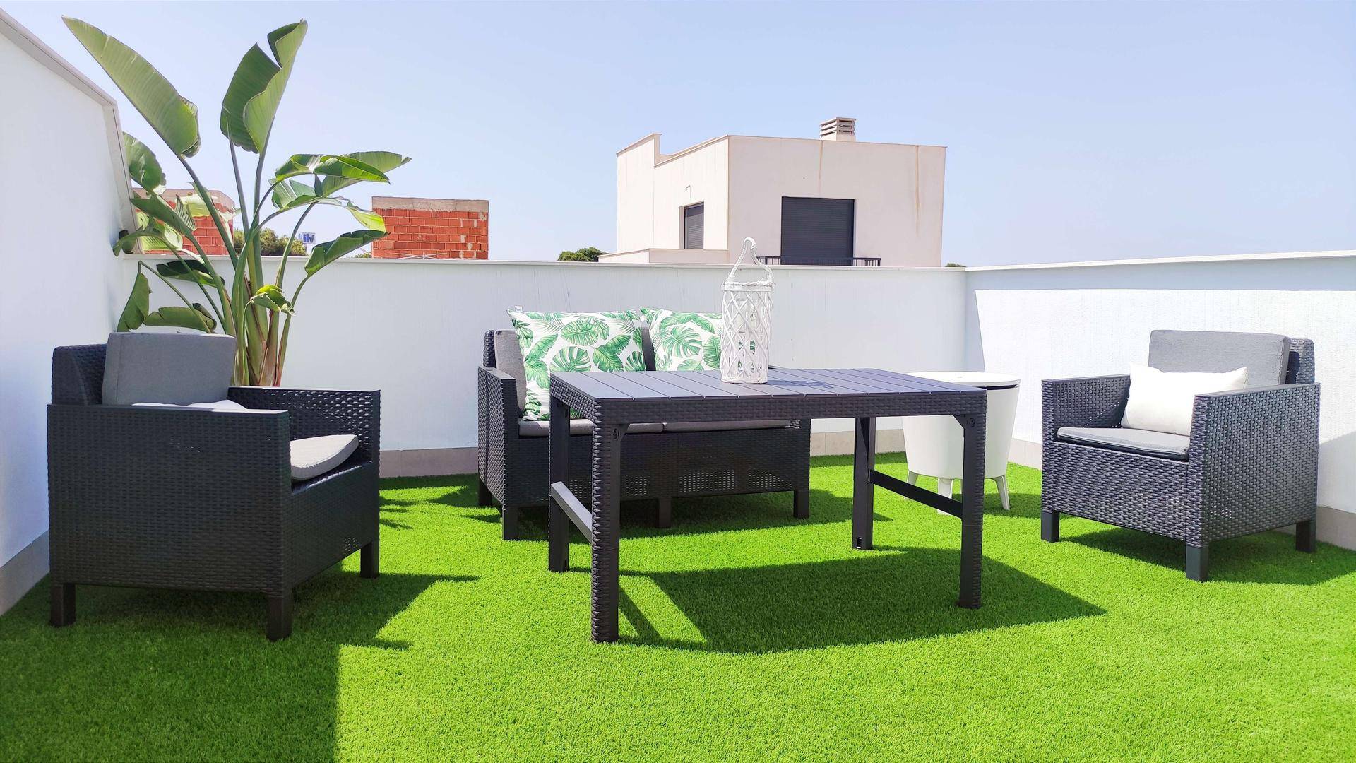 Große Dachterrasse mit Kunstrasen, bequemen Sitzmöbeln und Pflanzen.