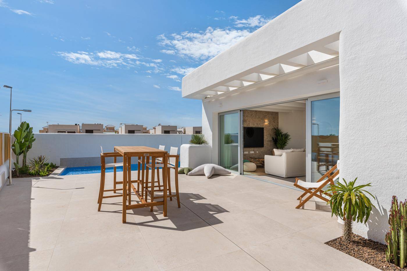 Sonniger Terrassenbereich mit Pool, Liegestuhl und Blick auf die umliegende Wohnbebauung.