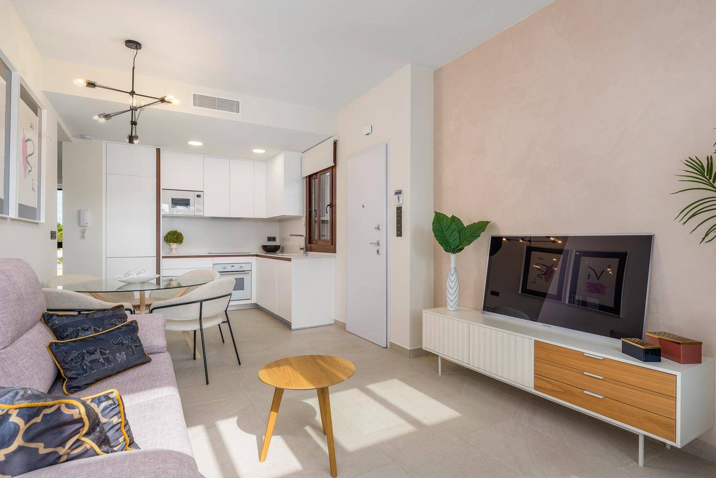 Geräumiger Wohn-Essbereich mit offener Küche, modernem Sofa und Zugang zum Außenbereich.