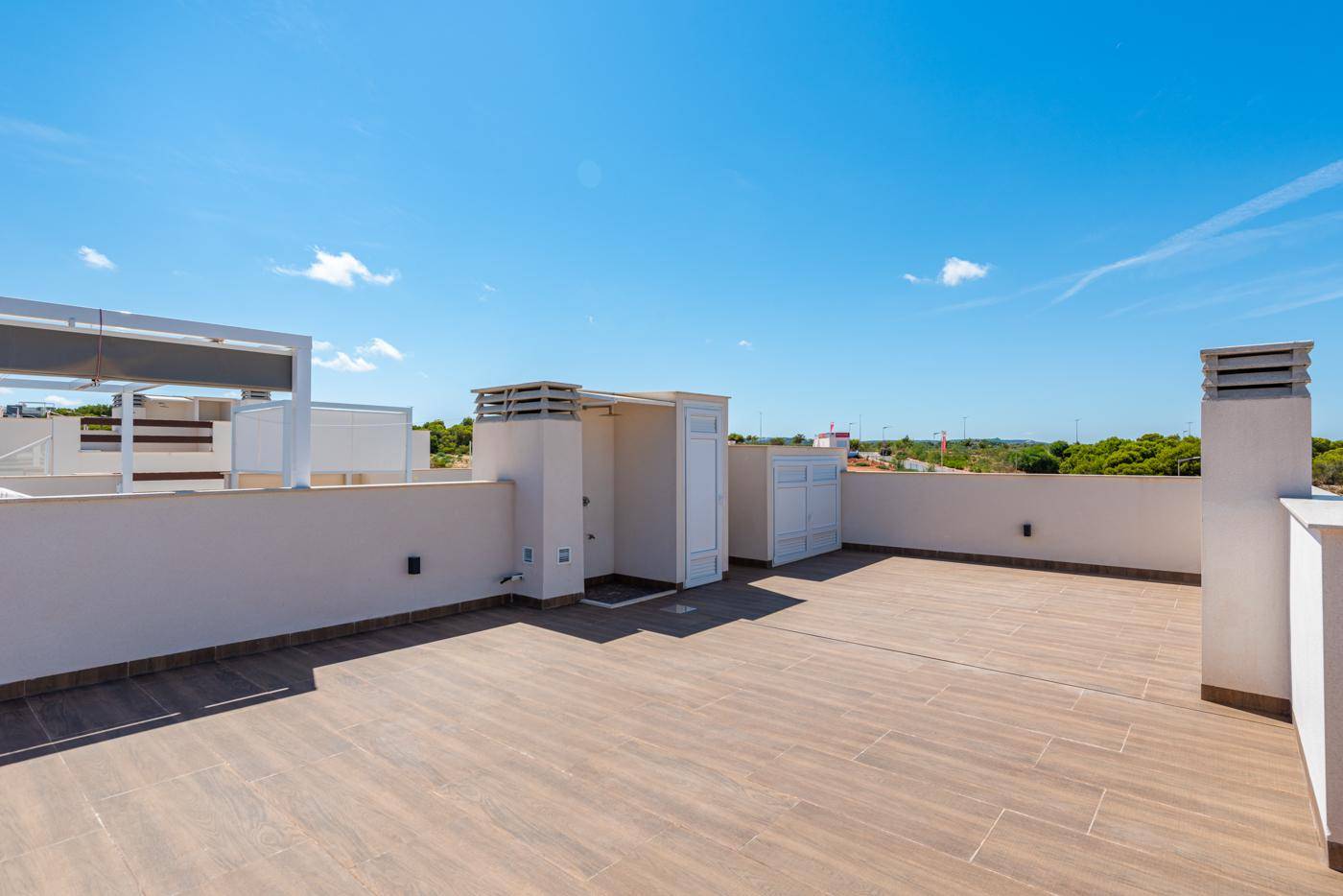 Geräumige Dachterrasse mit Fliesenboden und weitem Blick unter strahlend blauem Himmel.