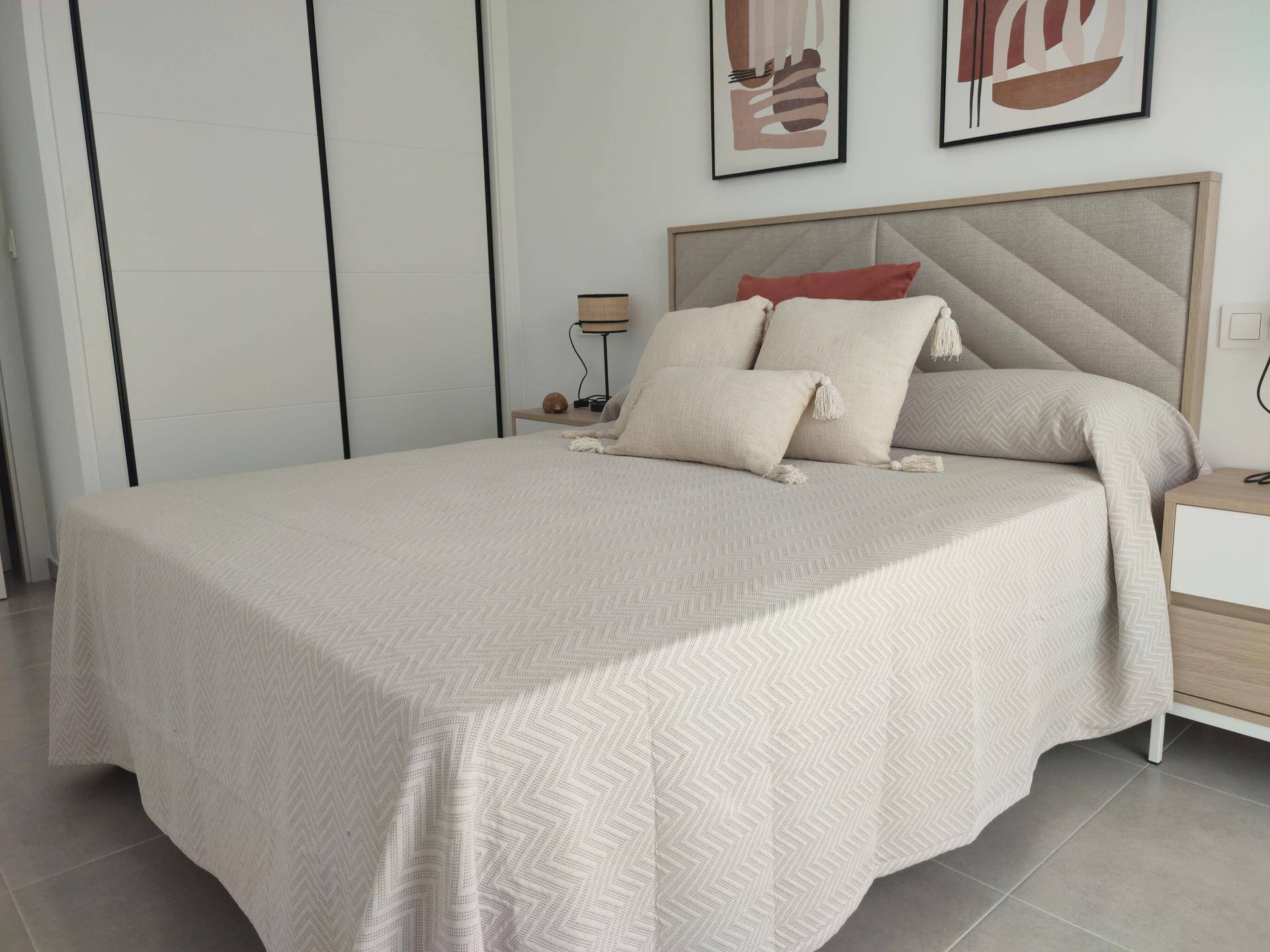 Modernes Schlafzimmer mit großem Bett, stilvollem Kopfteil und integriertem Kleiderschrank.