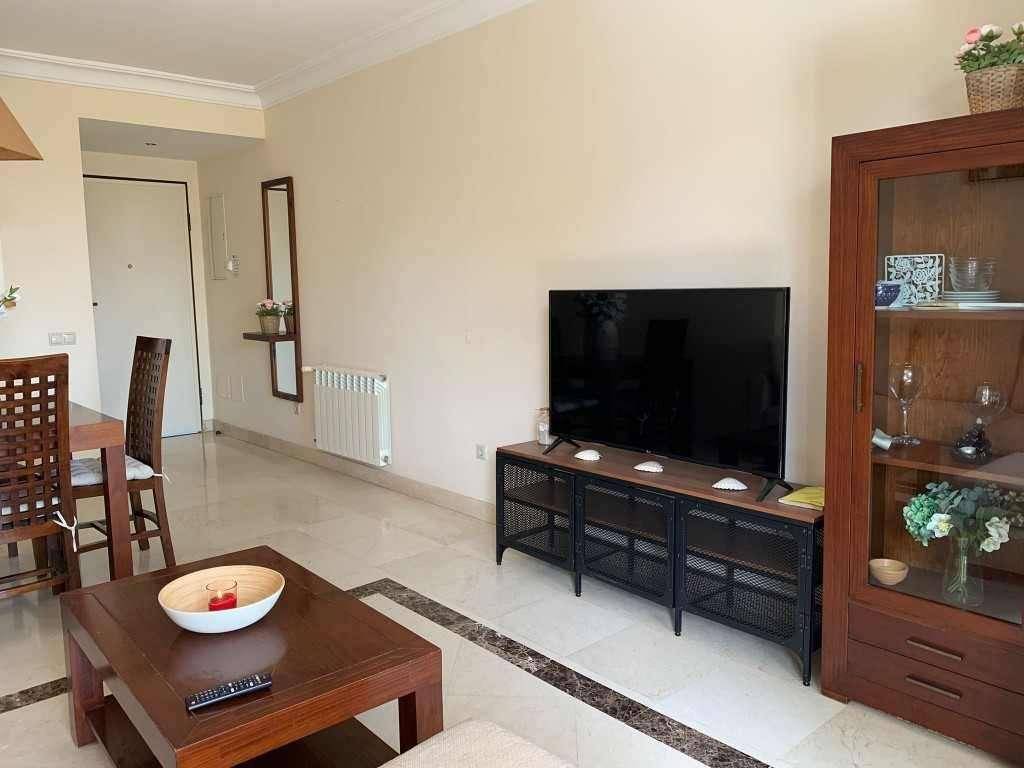 Geräumiger Wohnbereich mit Fernseher, Couchtisch und Blick auf den Essbereich.