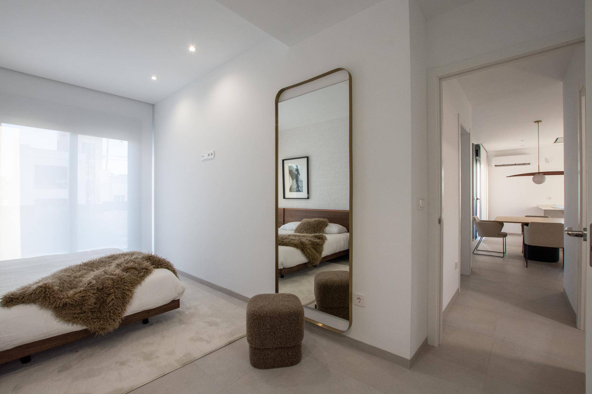 Helles Schlafzimmer mit großem Spiegel und Zugang zum offenen Wohnbereich.