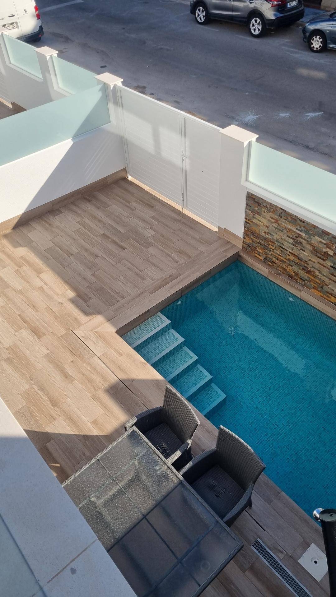 Übersicht des privaten Pools mit Treppe und angrenzender Holzterrasse für Entspannung.
