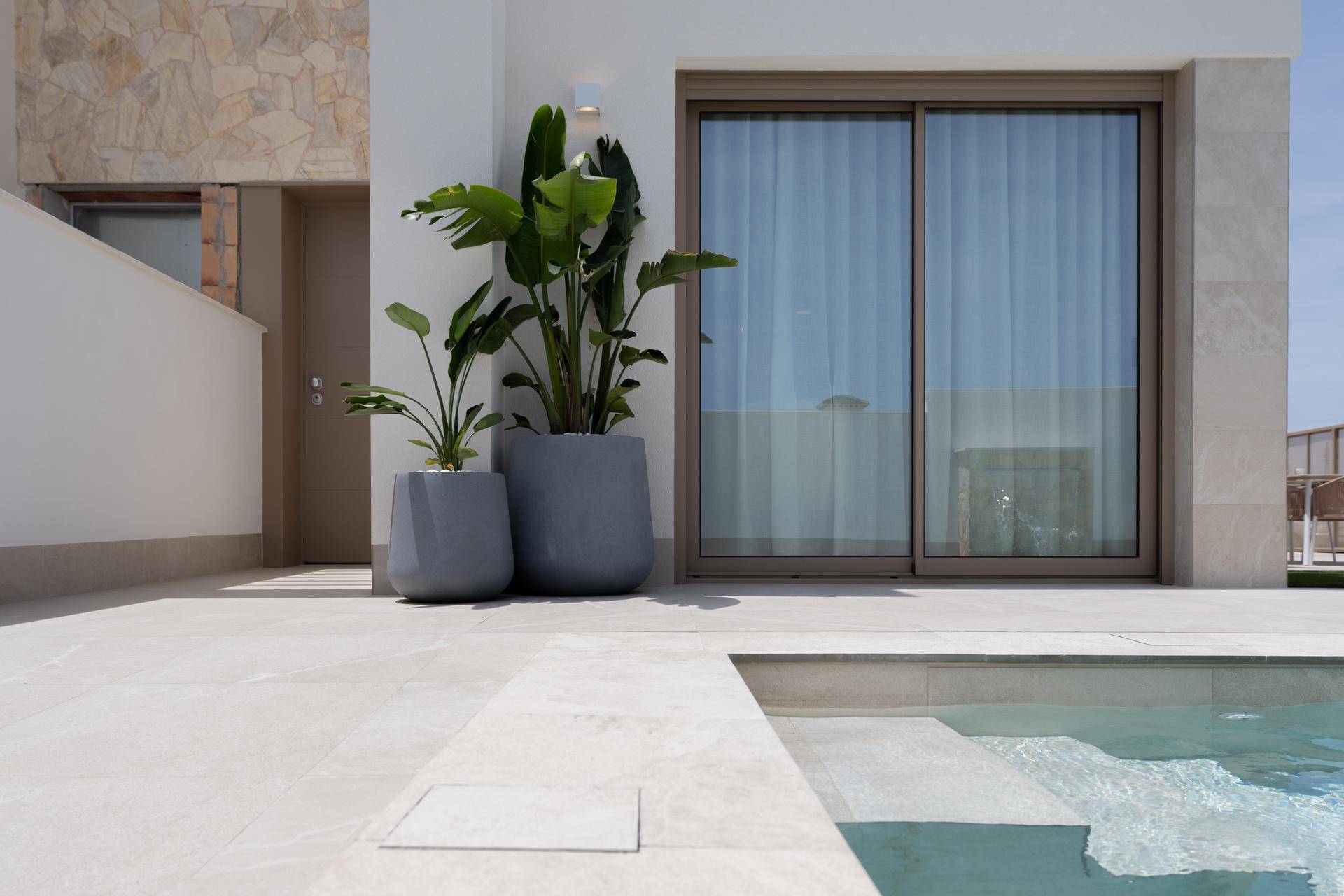 Moderne Villa mit privatem Pool, großen Schiebetüren und hellen Fliesen im Außenbereich.