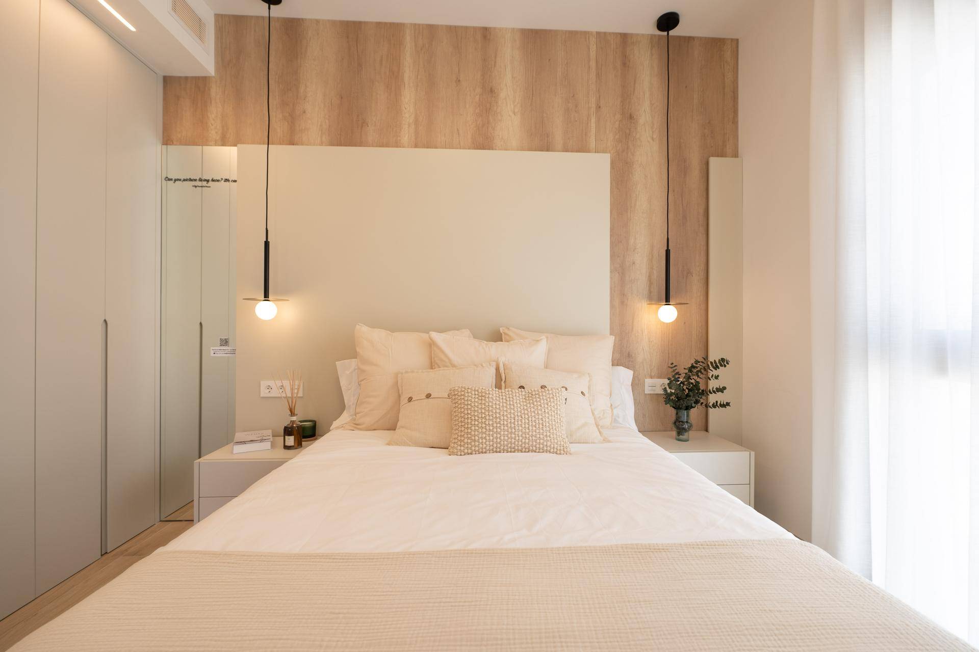 Helles Schlafzimmer mit beigem Kopfteil, Einbauschränken und stilvoller Dekoration.