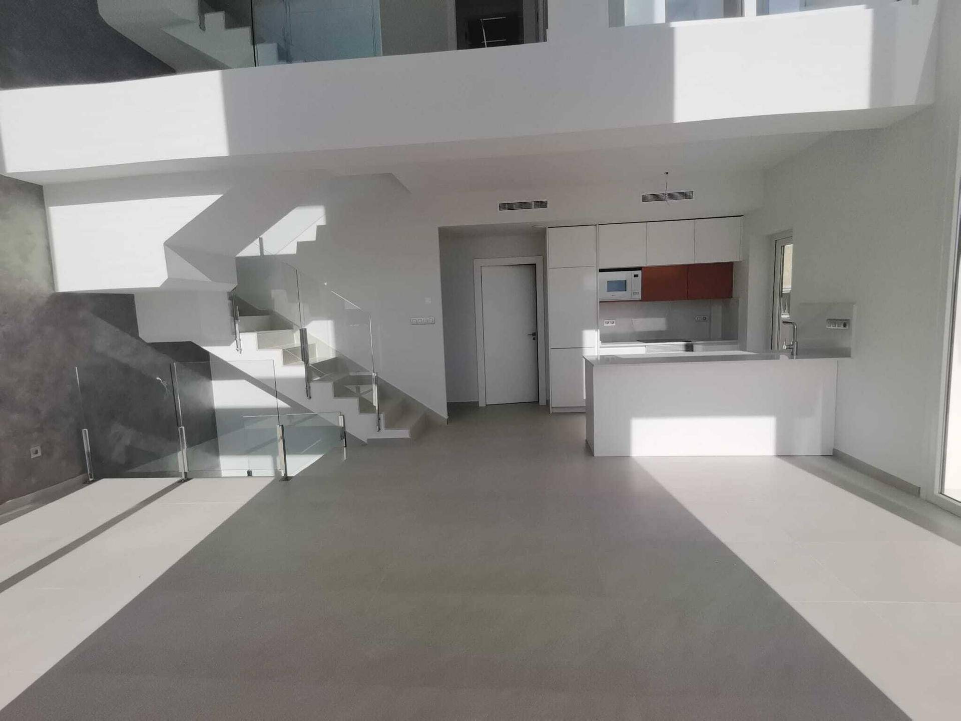 Offener Wohnbereich mit integrierter Küche und moderner Treppe, die die Etagen elegant verbindet.