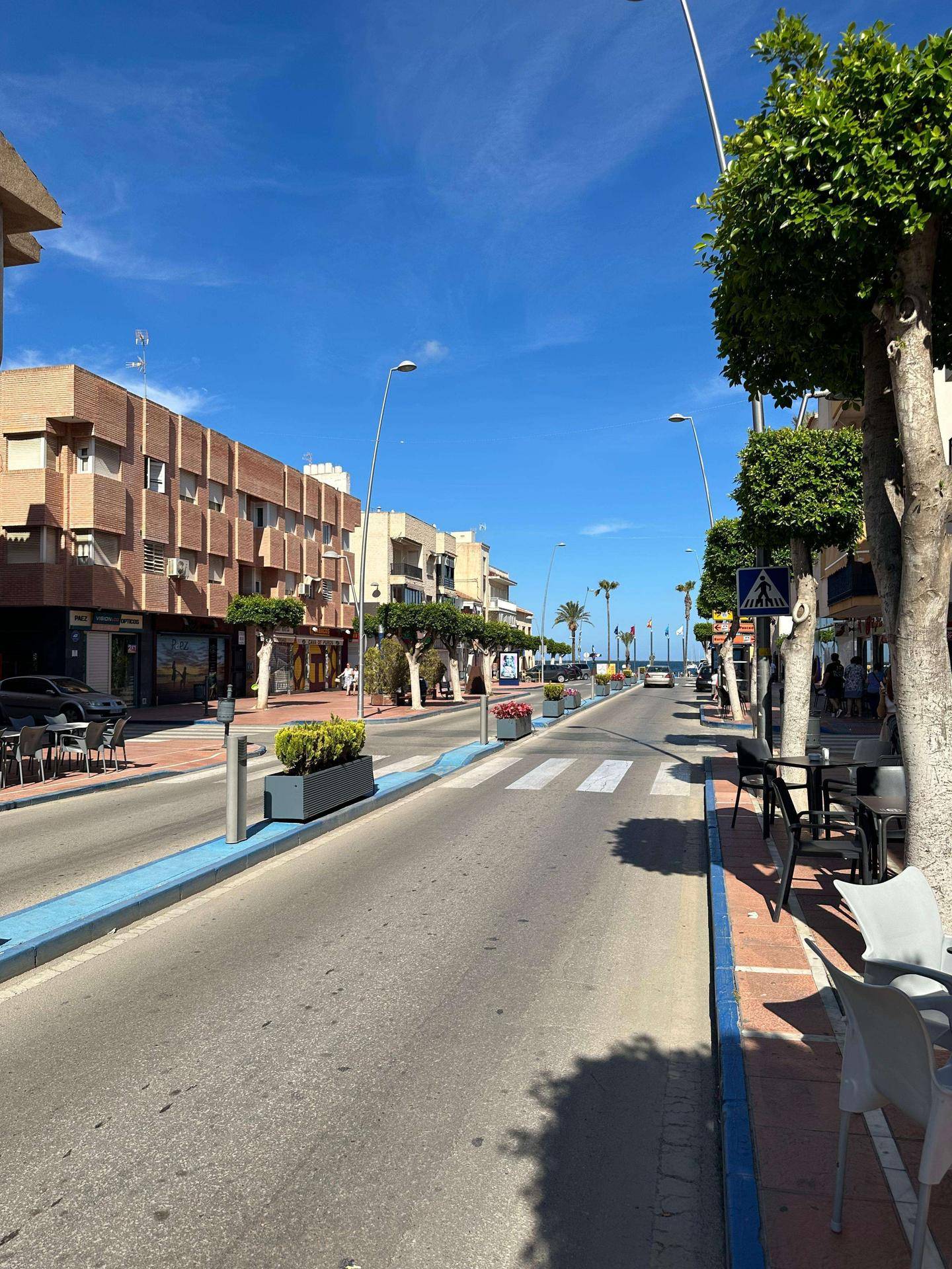 Blick auf die belebte Straße mit Geschäften, Cafés und Bäumen in der Nachbarschaft.