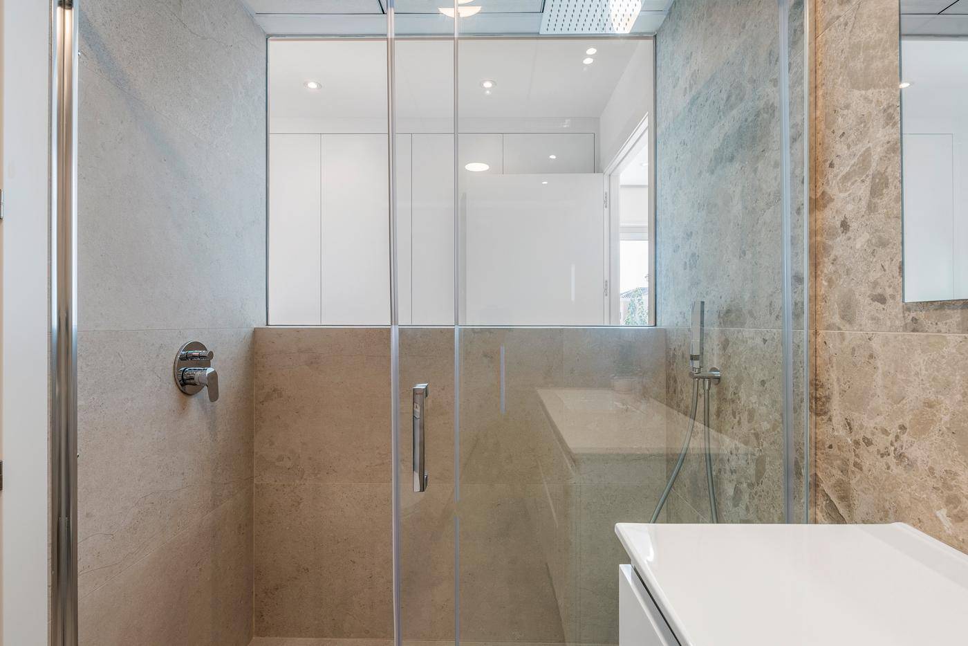 Modernes Badezimmer mit begehbarer Dusche und beigefarbenen Marmorfliesen.