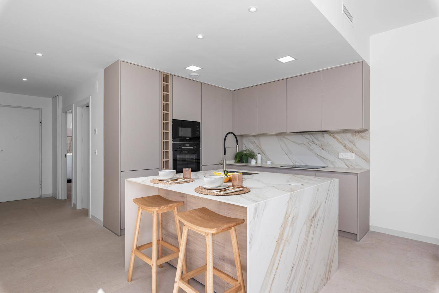 Moderne Küche mit Kochinsel, integrierten Geräten und minimalistischem Design.