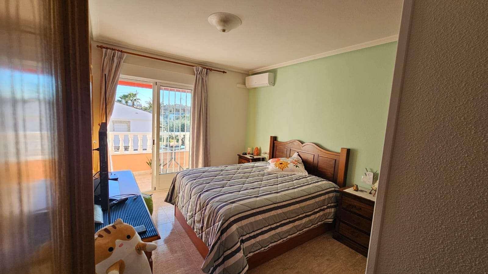 Schlafzimmer mit Doppelbett, Klimaanlage und Zugang zu einem sonnigen Balkon.