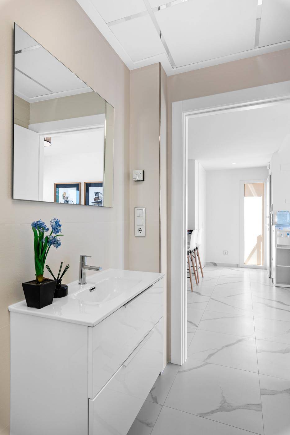 Modernes Badezimmer mit Waschtisch und Spiegel, offen zum hellen Flur.