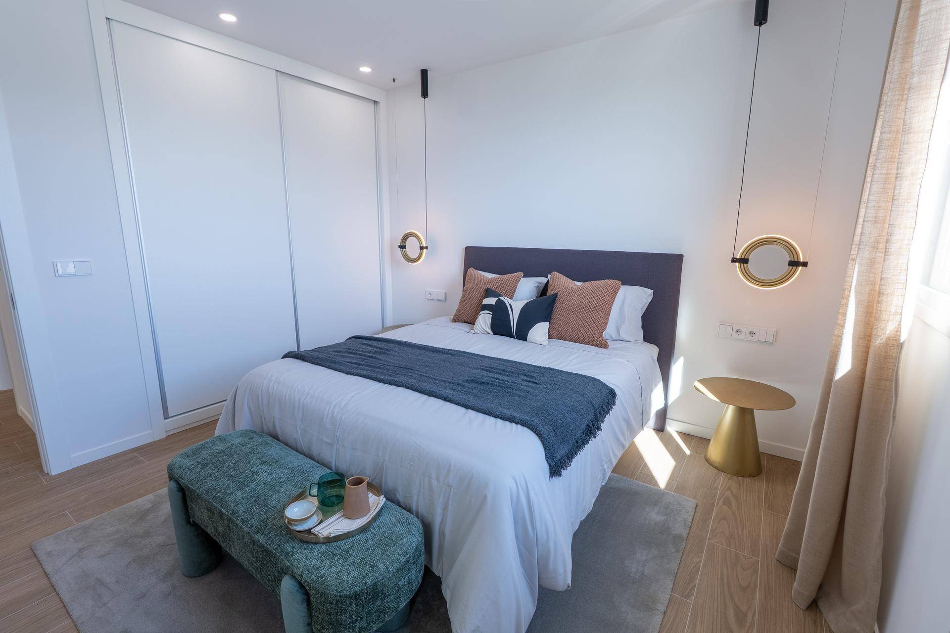 Modernes Schlafzimmer mit Doppelbett, Einbauschrank und stilvollen Nachttischlampen.