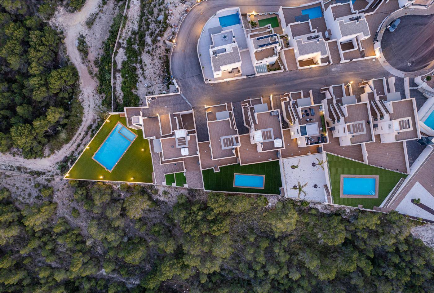 Vogelperspektive auf eine Wohnanlage mit mehreren Pools und begrünten Dachterrassen.