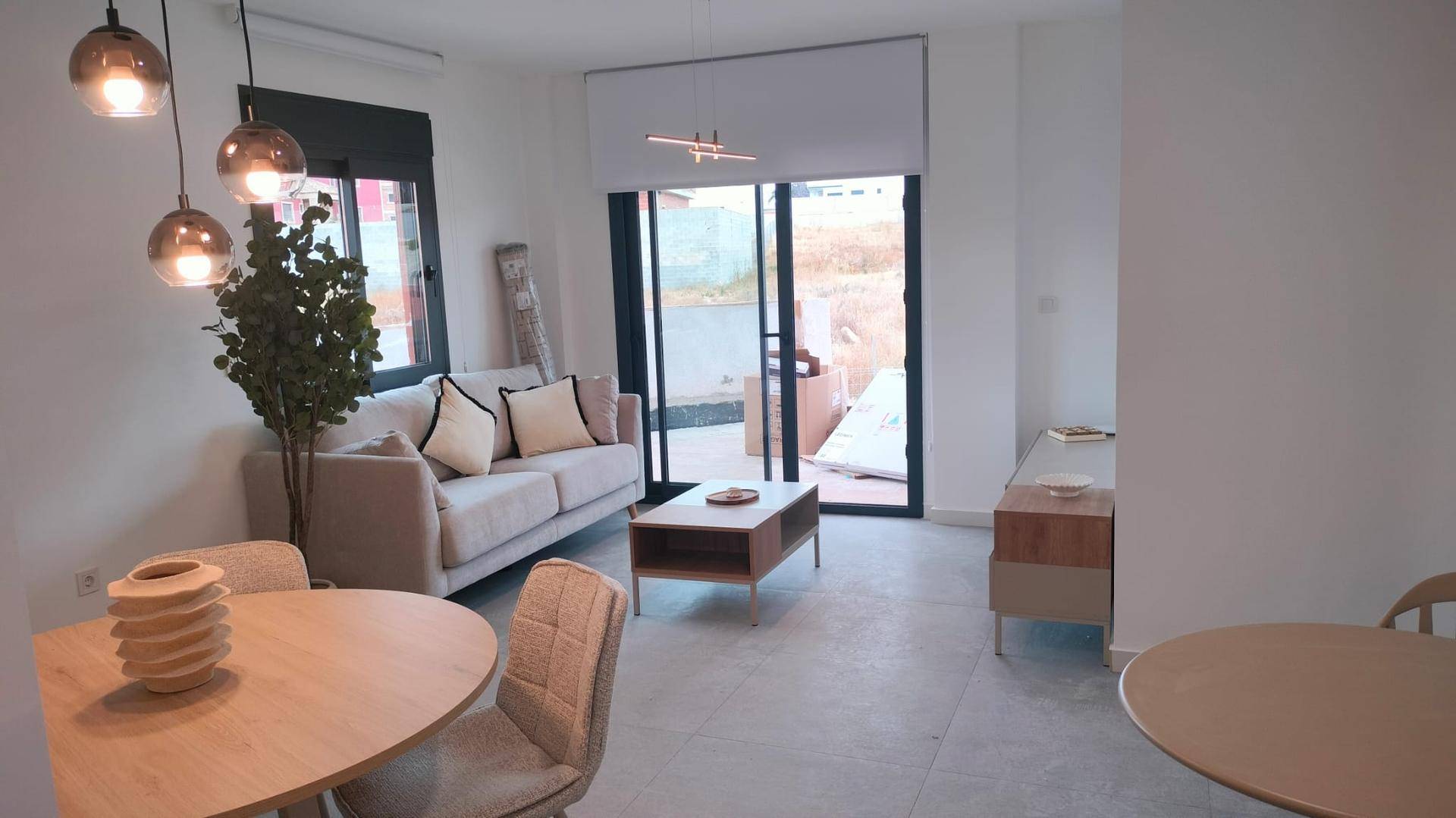 Geräumiger Wohn-Essbereich mit Sofa, Esstisch und Zugang zu einem Außenbereich.