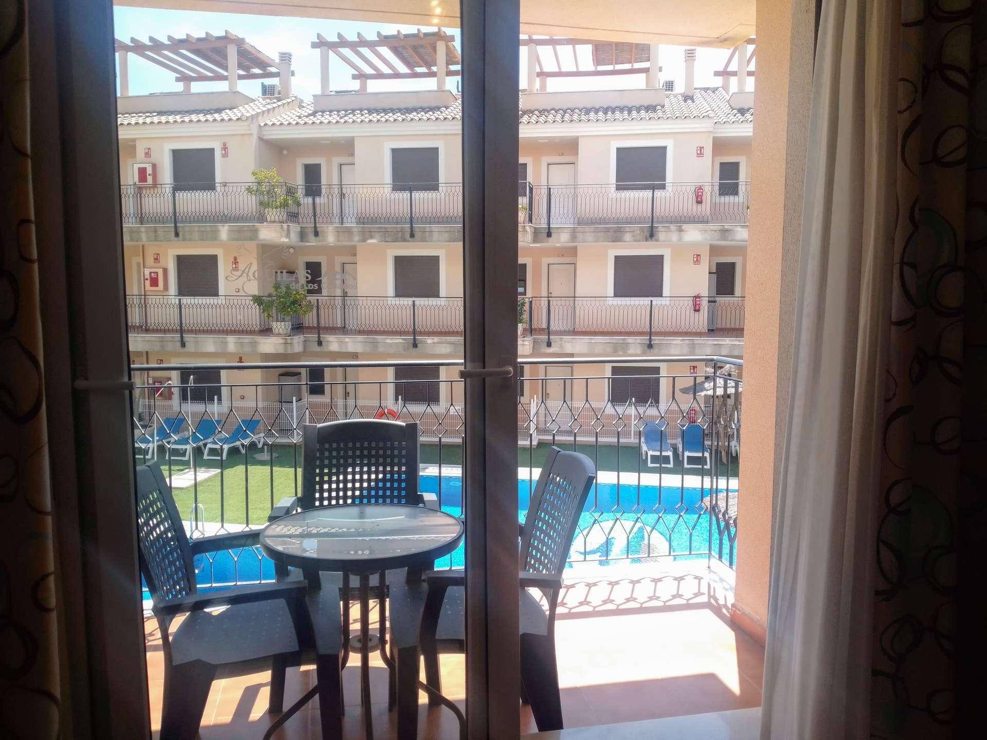 Balkon mit Sitzgelegenheiten und direktem Blick auf den Gemeinschaftspool der Anlage.
