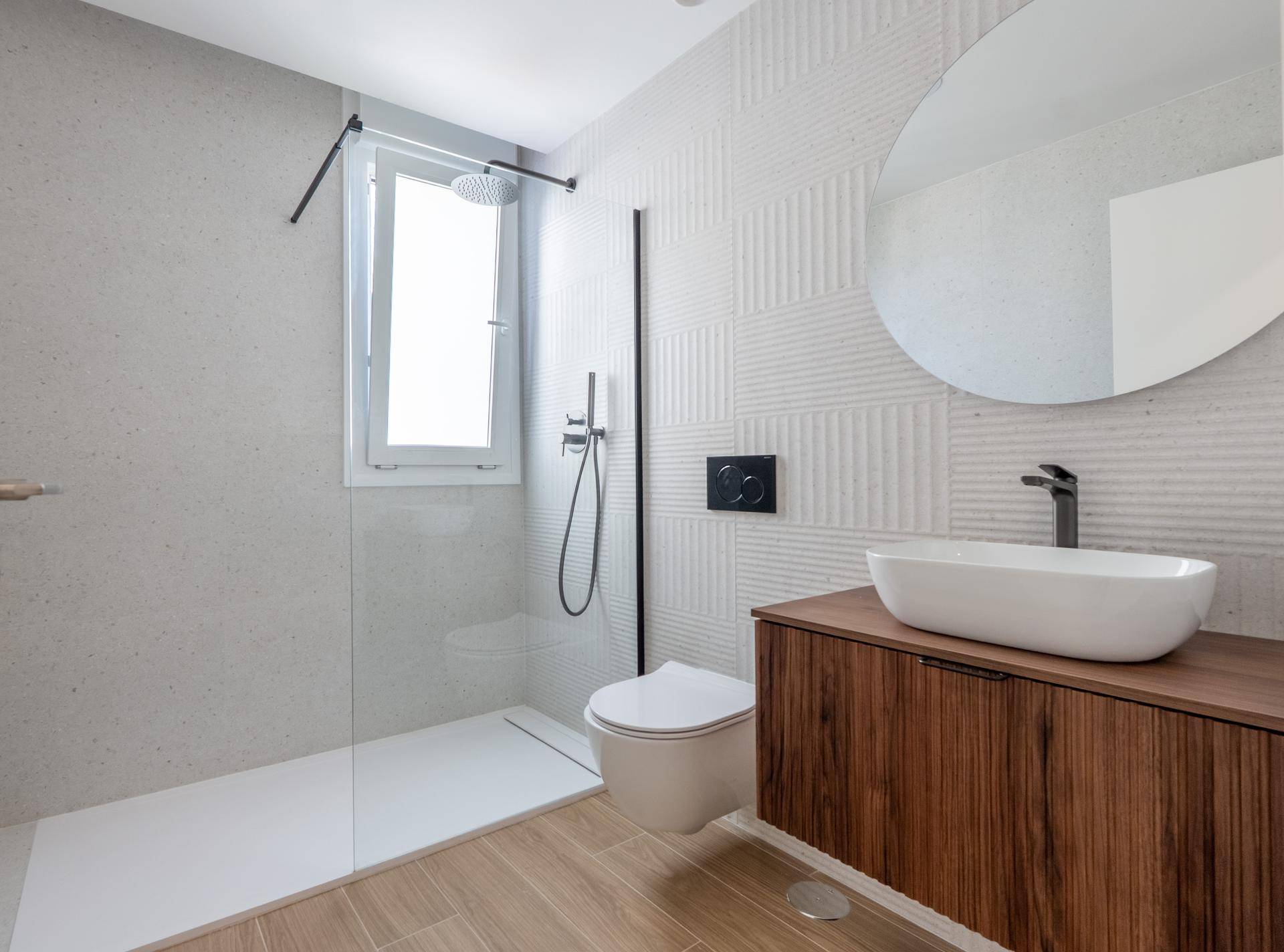 Stilvolles Badezimmer mit begehbarer Dusche, dunklem Holzwaschtisch und modernen Fliesen.