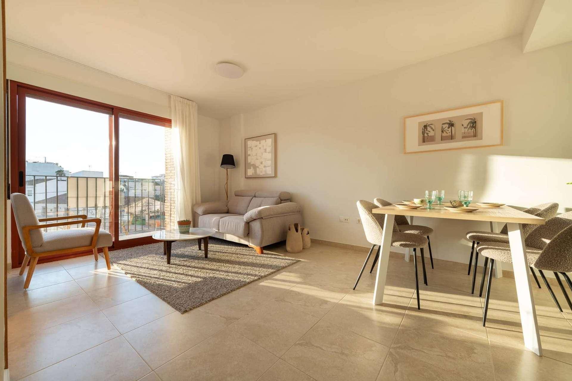 Helles Wohn-Esszimmer mit Fliesenboden, beigem Sofa und Zugang zu einem französischen Balkon.